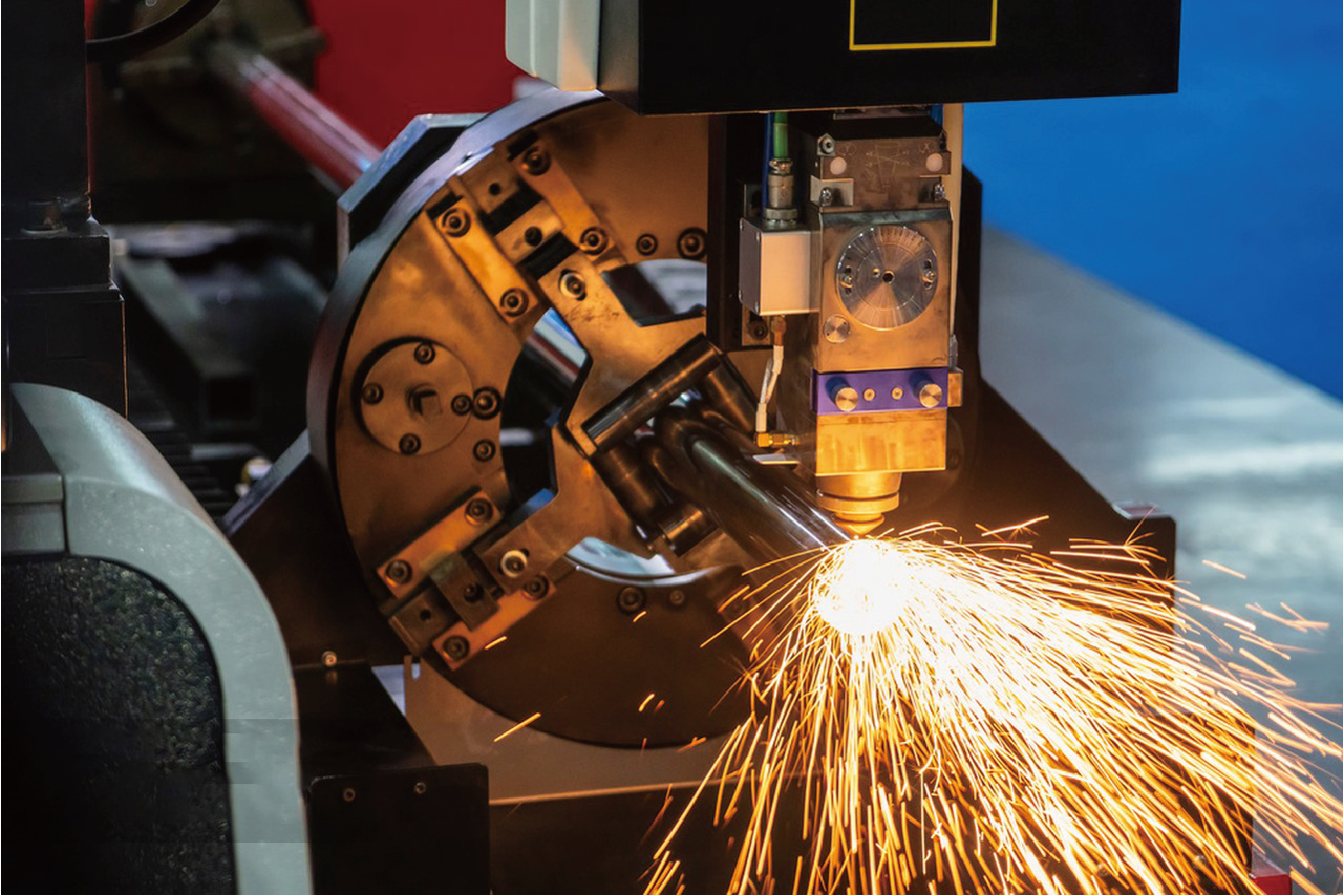 Close-up of intelligent laser cutting head performing precise tube cutting with intense spark emission.