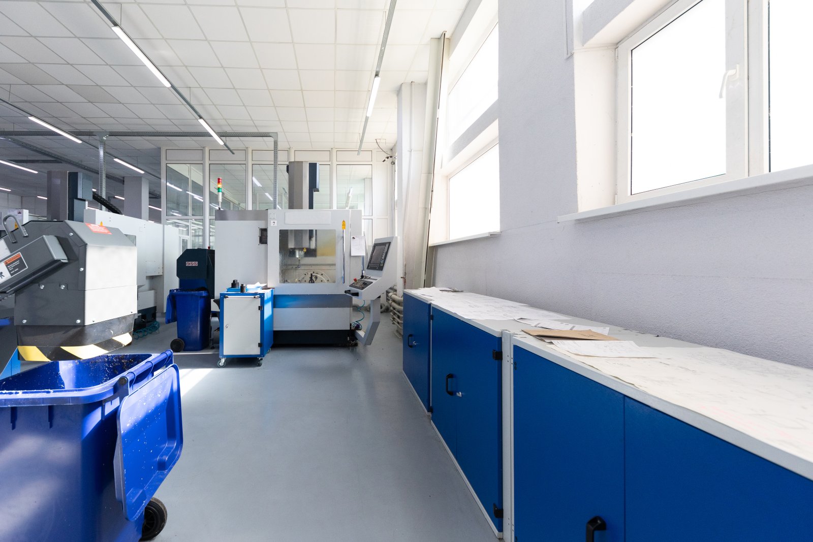Control area with blue cabinets and CNC stations in precision machining workshop