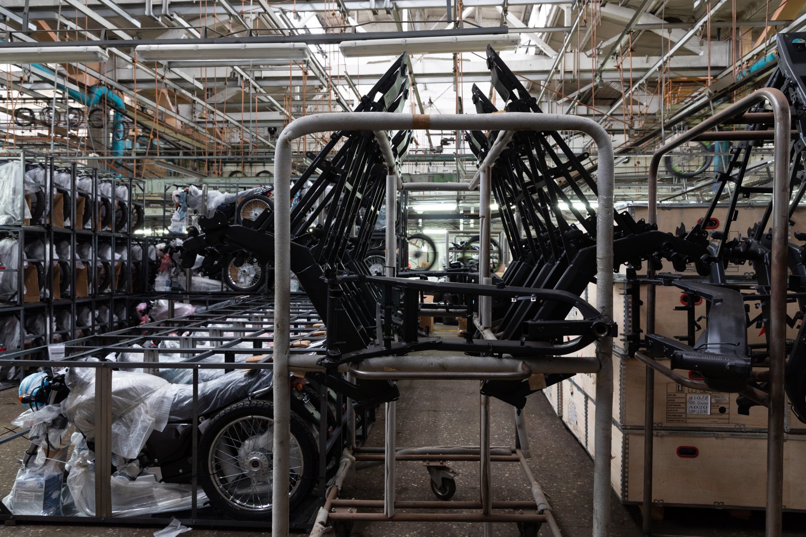Motorcycle frame assemblies stacked in bulk, showing mass production of welded tubular structures