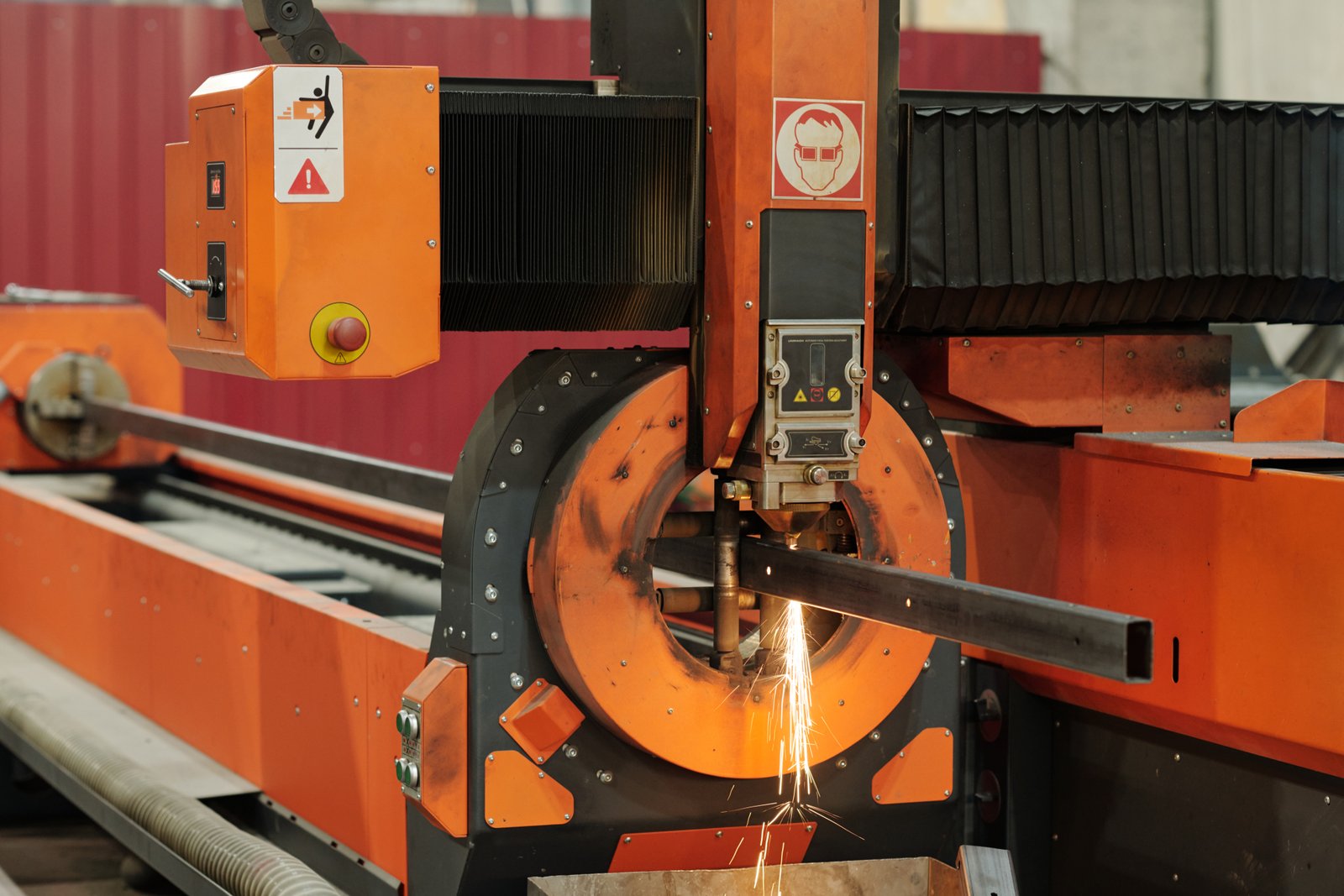 High-speed pipe laser cutting with square hollow section. Orange body equipment shows steady operation and spark output.