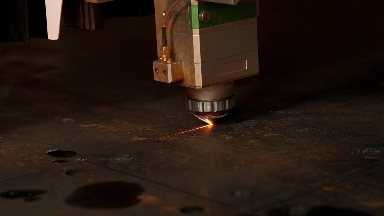 MZBNL laser head cutting stainless steel tube with complex mesh-like patterns and high-speed spark trails.