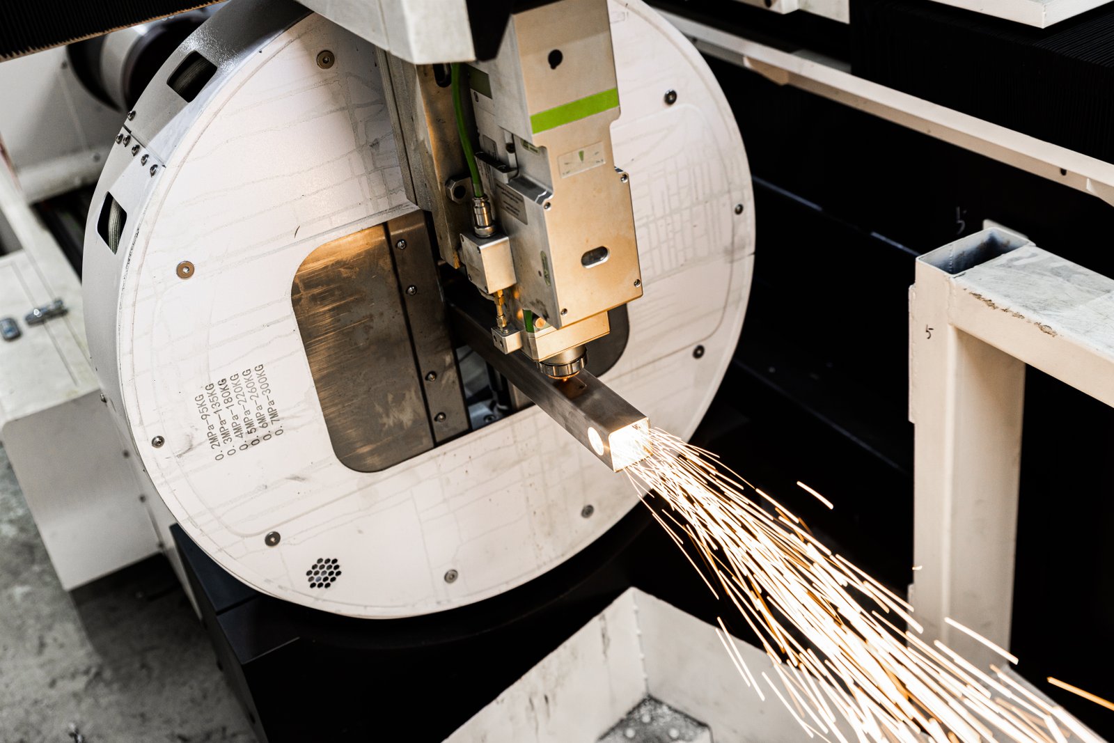 Industrial fiber laser machine processing square pipe with automated chuck.