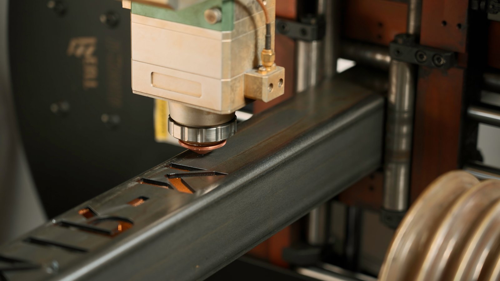 Industrial laser tube cutter slicing through square metal tube with sparks.